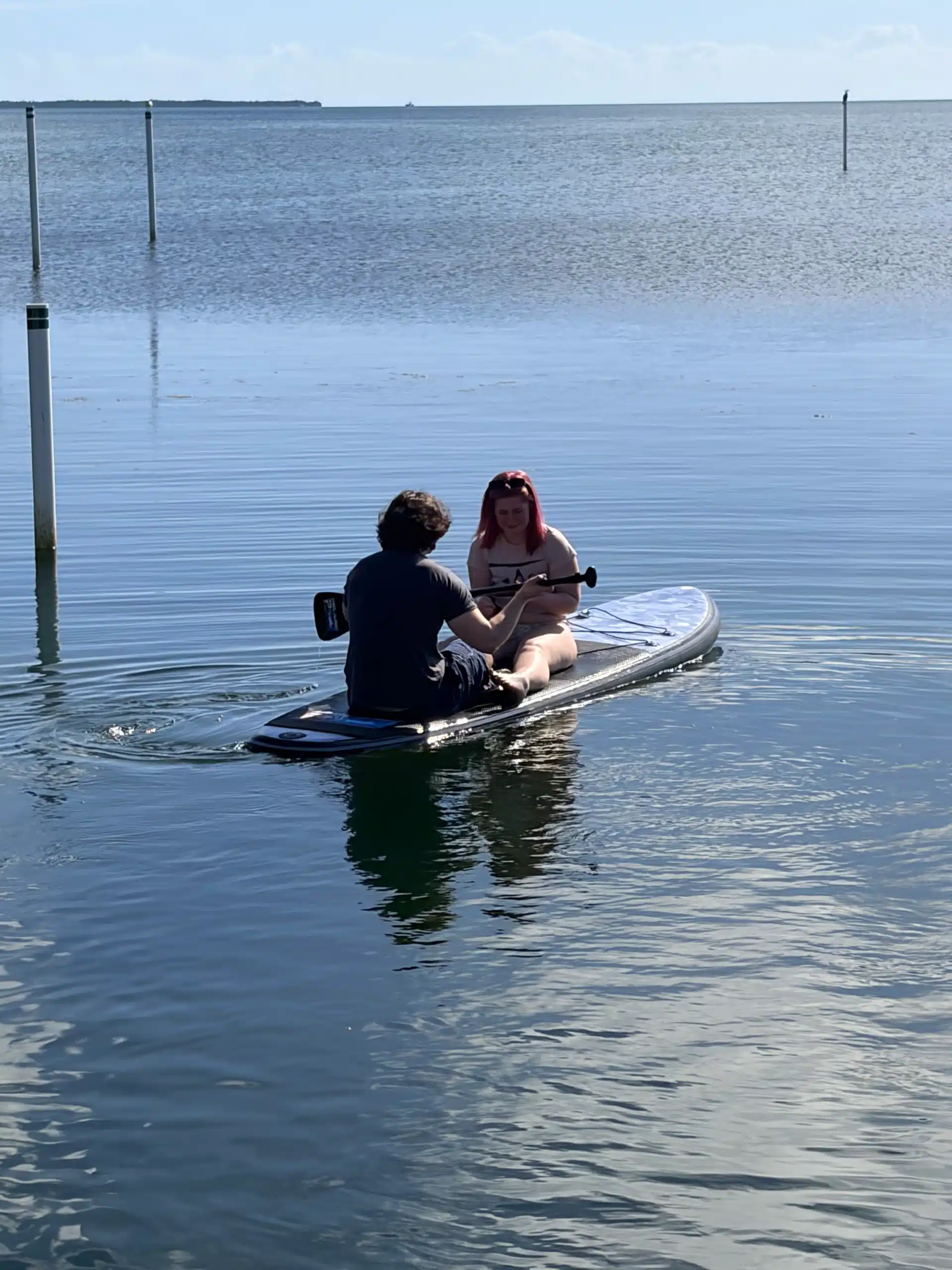 My son and his girlfriend sitting on paddleboards in calm Florida ocean water during our family vacation, creating peaceful memories together.