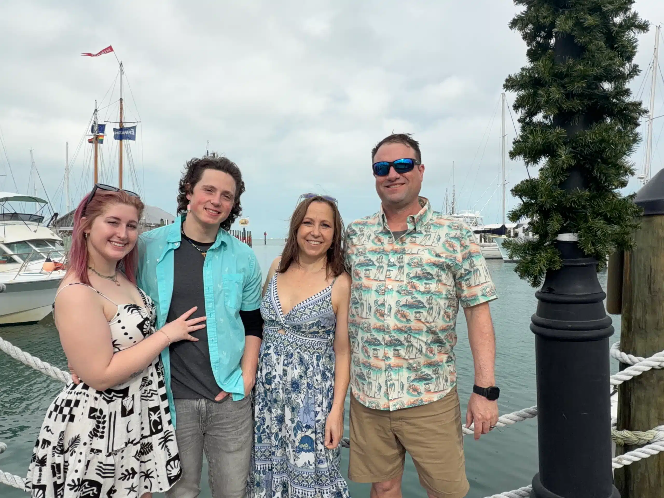 Our family smiling together at a marina in Florida during vacation, standing in front of boats and calm water.